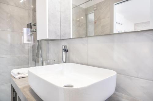 a white bathroom with a sink and a mirror at Relais Roma Beach in Fregene
