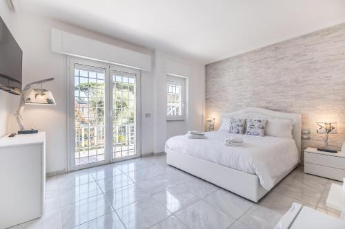 a white bedroom with a large bed and windows at Relais Roma Beach in Fregene
