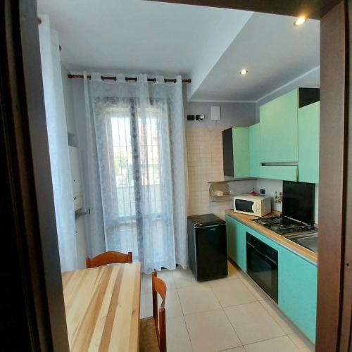 a kitchen with green cabinets and a table and a window at B&B linate in Peschiera Borromeo