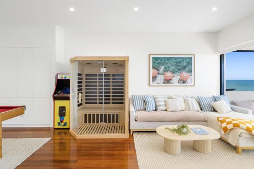 a living room with a couch and a table at Henley Beachfront Luxury Home With Sauna Just 200m From Henley Square! in Henley Beach