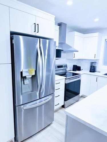 a stainless steel refrigerator in a kitchen with white cabinets at Luxury 3-Bedroom Full House Near Magnetic Hill in Moncton