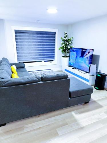 a living room with a black couch and a laptop at Luxury 3-Bedroom Full House Near Magnetic Hill in Moncton