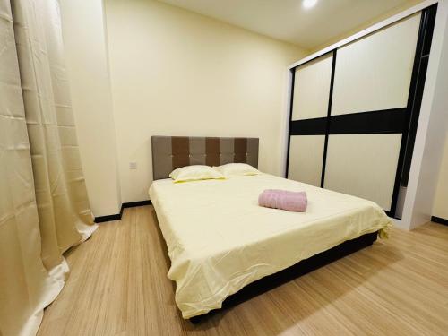 a bedroom with a bed with a pink pillow on it at City Apartment next to The Spring in Bintulu