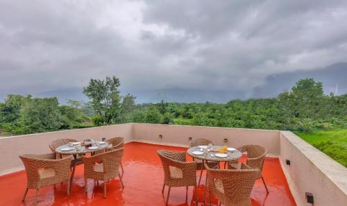 a patio with tables and chairs on a balcony at SaffronStays Grand Odyssy in Jambrung 
