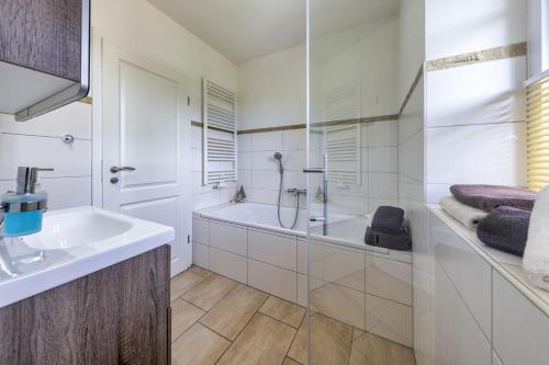 a white bathroom with a sink and a shower at Haus Wind&Wellen, Wohnung Hafen in Wittdün