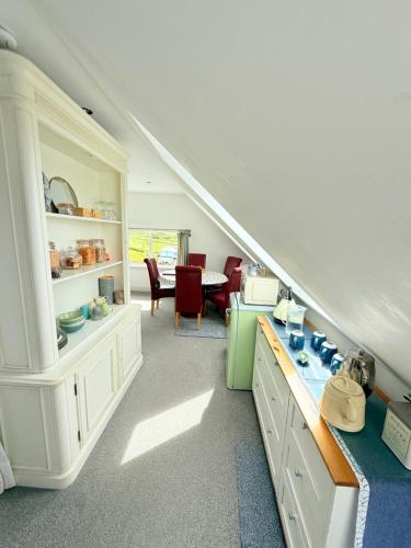 a kitchen with white cabinets and a table with red chairs at Clouds B&B in Kilmuir