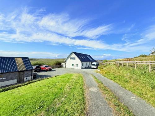 a dirt road leading to a white house with a barn at Clouds B&B in Kilmuir
