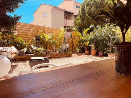 a backyard with a wooden table and chairs and plants at Appartement - Sanary-sur-Mer in Sanary-sur-Mer