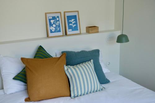 ein weißes Bett mit blauen und weißen Kissen darauf in der Unterkunft Araça Studio - Atlantic Mountain Living in São Vicente