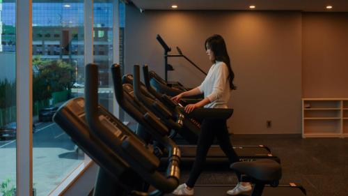 a woman walking on a treadmill in a gym at Workers Hotel Daejeon by Aank in Daejeon