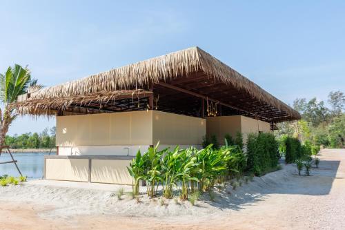 a building with a straw roof on a beach at Camp Cayla - COASTA in Ban Ao Makham Pom
