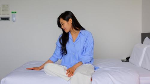 a woman in a blue shirt sitting on a bed at Workers Hotel Daejeon by Aank in Daejeon