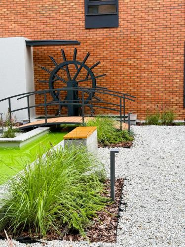 a garden with a water wheel next to a brick building at Justinrent PALATIUM 13 in Legnica