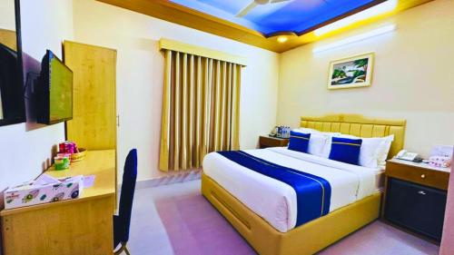 a bedroom with a bed and a desk and a television at The Ambassador Hotel Dhanmondi in Dhaka
