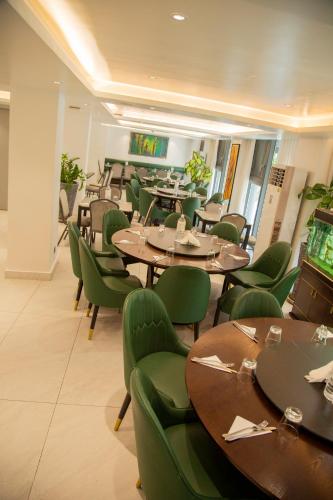 a restaurant with wooden tables and green chairs at AXIL HÔTEL in Dakar