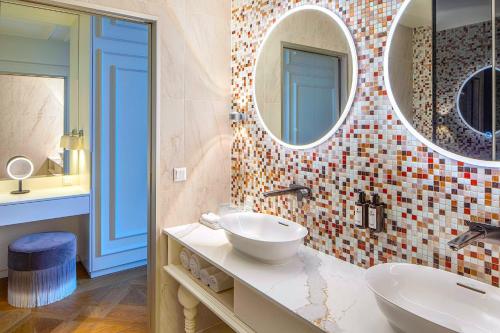 a bathroom with two sinks and two mirrors at Kimpton BEM Budapest by IHG in Budapest