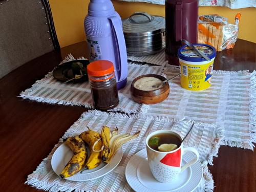a table with a plate of bananas and a cup of coffee at Quaint Serene Homes in Busia