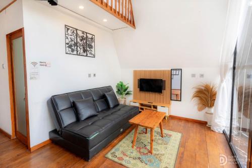 a black leather couch in a living room with a tv at Zaa Villa in Dieng