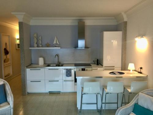 Una cocina con gabinetes blancos y sillas blancas. en Caballito de mar seahorse, en Playa Blanca
