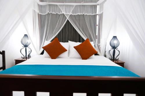Schlafzimmer mit einem Bett mit orangefarbenen und blauen Kissen in der Unterkunft Cinnamon Crest Resort & Ayurveda Spa in Kandy