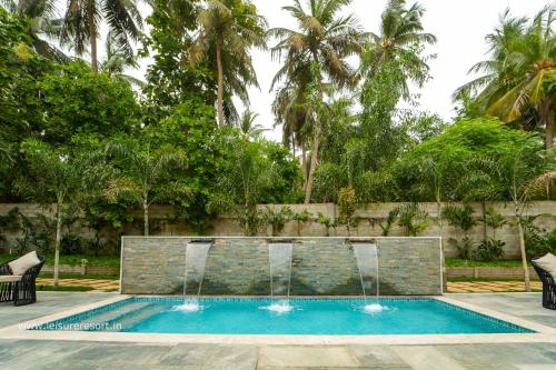 a swimming pool with two fountains in a yard at Leisure Resort in Pondicherry