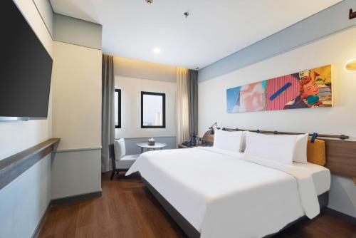 a hotel room with a white bed and a tv at ARTOTEL Hub Simpang Temu Jakarta in Jakarta