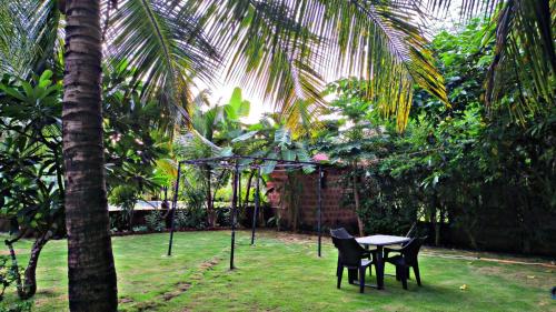 a table and chairs in a garden with a palm tree at Leela beachside stay in Kashid
