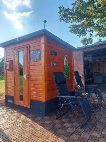 a small wooden cabin with two chairs on a patio at Apartma Žirovnik in Cerklje na Gorenjskem
