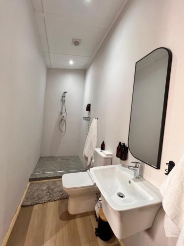 Un baño blanco con lavabo y espejo. en Whispering Thorns Off-Site Apartment, en White River