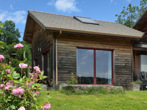 a log cabin with a window and pink roses at Refuge de La Coste 