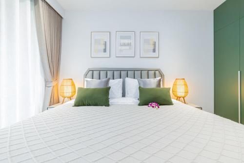 a bedroom with a white bed with green and white pillows at Beachside 2 bedrooms apartment 200 meters to Bang Tao Beach Manage by OCEAN HUB in Bang Tao Beach