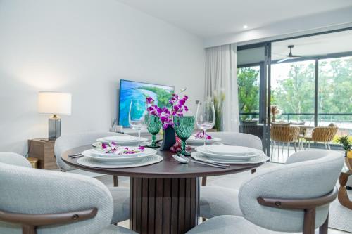 a dining room with a table with plates and flowers on it at Beachside 2 bedrooms apartment 200 meters to Bang Tao Beach Manage by OCEAN HUB in Bang Tao Beach