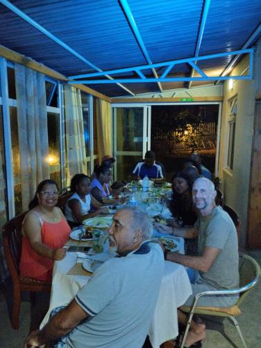 a group of people sitting at a table eating at Le Macoua Guest House in Nouvelle Découverte