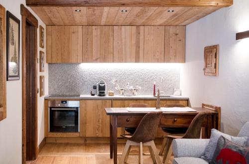 a kitchen with a table and some chairs in a room at Au Coeur Des Neiges Resort SPA & FREE E-BIKE in Courmayeur