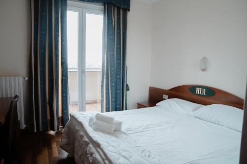 a bedroom with a white bed with a large window at Hotel Ristorante La Rampina in Vimodrone