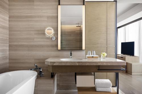a bathroom with a sink and a tub and a mirror at Shanghai Marriott Hotel Kangqiao in Shanghai
