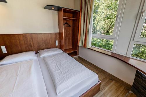 a small bedroom with two beds and a window at smartMotel in Kempten