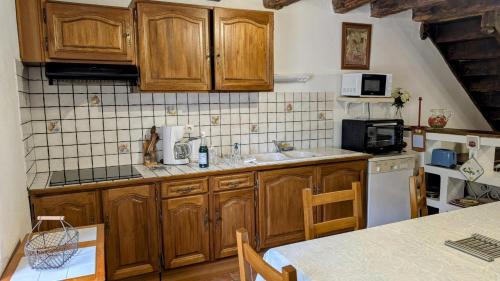 a kitchen with wooden cabinets and a counter top at La ferme des souvenirs in Vaulry
