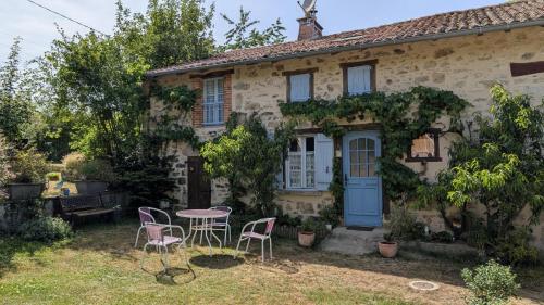 a house with a table and chairs in the yard at La ferme des souvenirs in Vaulry
