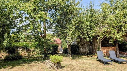 two chairs sitting in a yard with trees at La ferme des souvenirs in Vaulry