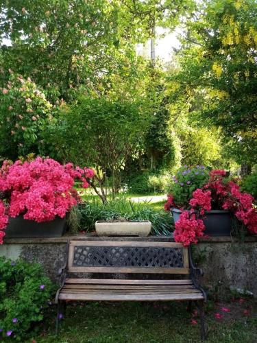 a bench in a garden with flowers and plants at La ferme des souvenirs in Vaulry