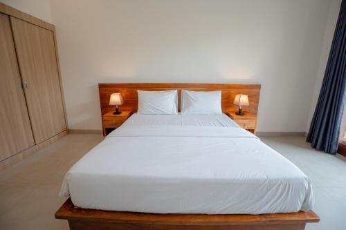a bedroom with a large white bed with two lamps at Abimanyu Guest House in Seminyak