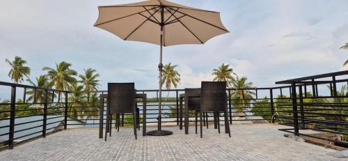 a table and two chairs with an umbrella at Fiya Inn in Maalhos