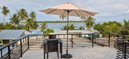 a patio with a table and an umbrella at Fiya Inn in Maalhos