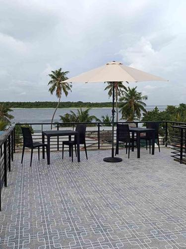 a patio with tables and chairs and an umbrella at Fiya Inn in Maalhos