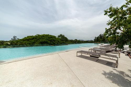 a swimming pool with lounge chairs next to the water at Beachside 2 bedrooms apartment 200 meters to Bang Tao Beach Manage by OCEAN HUB in Bang Tao Beach