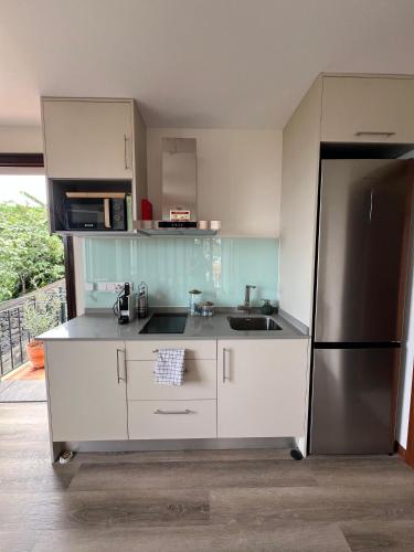 a kitchen with white cabinets and a stainless steel refrigerator at MadeiraLife in Seixal