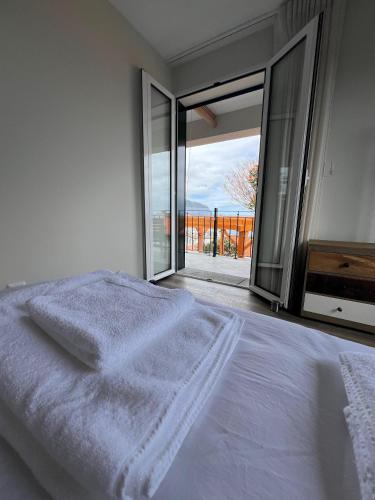 a white bedroom with a bed and a large window at MadeiraLife in Seixal