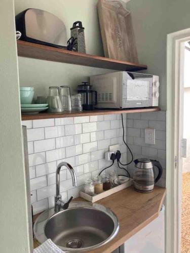 a kitchen counter with a sink and a microwave at Quaint Cottage Durban North in Durban