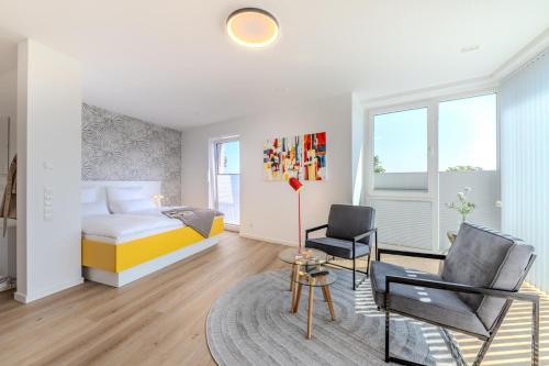 a bedroom with a bed and two chairs and a table at Stadtloft Penthouse "Eversten" Neubau Business Apartments für Projekt- und Firmenaufenthalte in Oldenburg